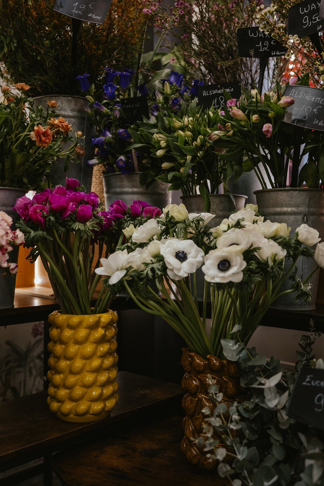 Anémones blanches et renoncules dans des vases jaunes